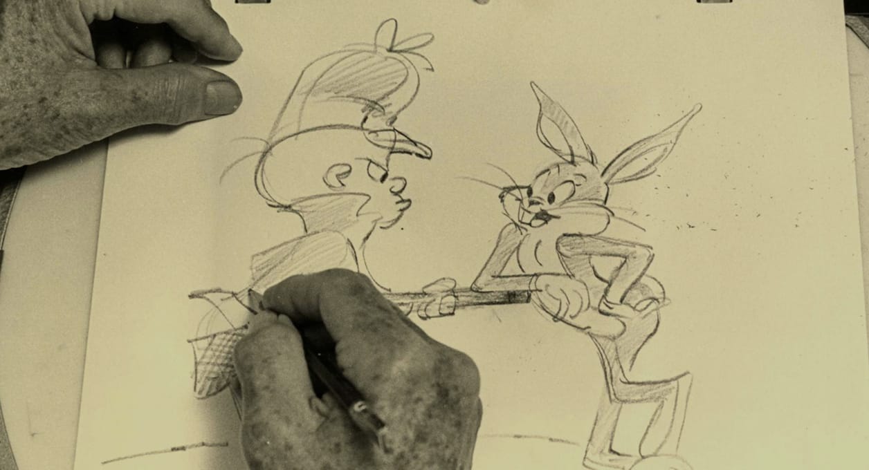 Hands sketching Bugs Bunny and Elmer Fudd in pencil on an animation drawing pad