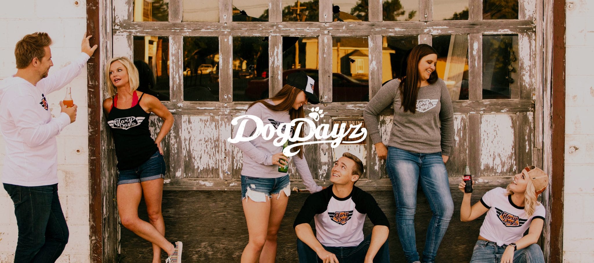 DogDayz banner over friends in branded apparel by a weathered garage door