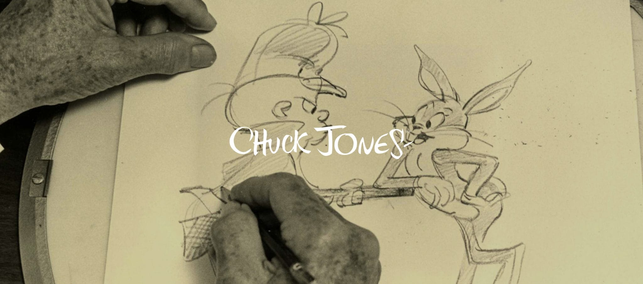 Chuck Jones banner over an archival photo of hands sketching Bugs Bunny and Elmer Fudd