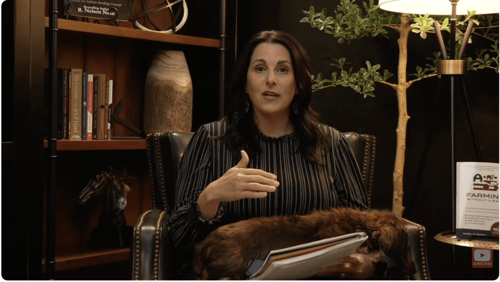 Mary Jo Irmen speaking to camera from a leather armchair, her Farming Without the Bank book displayed beside her